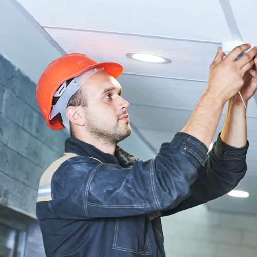 Handyman worker installing or checking smoke alarm detector on the ceiling